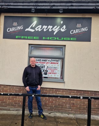 Larry owner stood in front bar signage