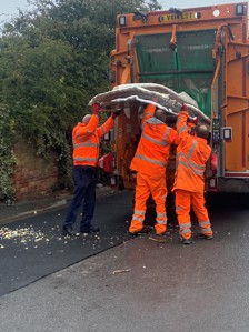 People in hiigh-vis load rubbish into a bin lorry