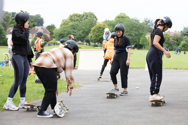 Young people on skate boards in a park wearing helmets