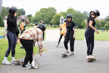Young people on skate boards in a park wearing helmets