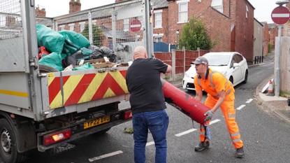 Two mean moving a large item in to the back of a truck