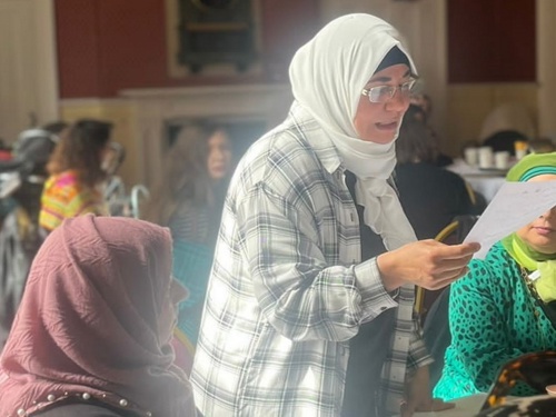 A woman reads to other women at a creative writing event