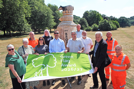 Councillors and environment officers holding up the green flag in front of the the Broxtowe sculpture at Bramcote Hills Park