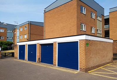 Block of garages with blue doors near blocks of housing