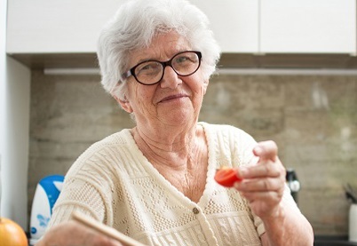 Elderley woman wearing glasses sitting in her kitchen