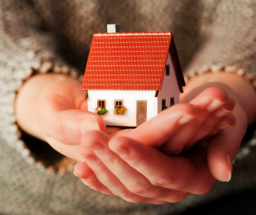 A hand holding a model house