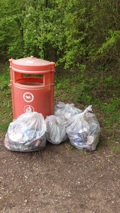 4 Litter bags full beside a waste bin