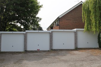 Great Hoggett Drive Garages - four white doors with tree hanging over the right one