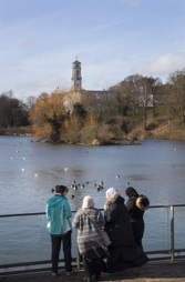 Four women stood in front of lake talking to each other