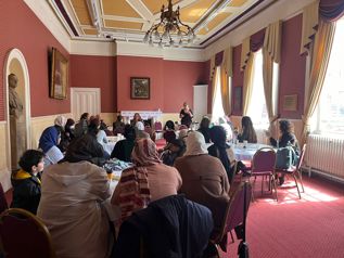 A group of women sat in a room listening to a speaker