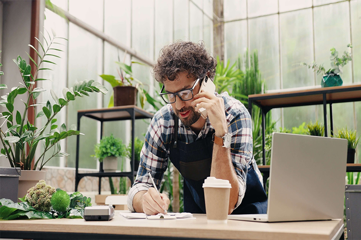 A man on the phone writing something down in his business space
