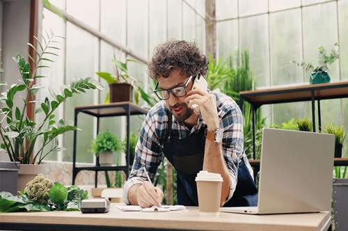 A man on the phone writing something down in his business space