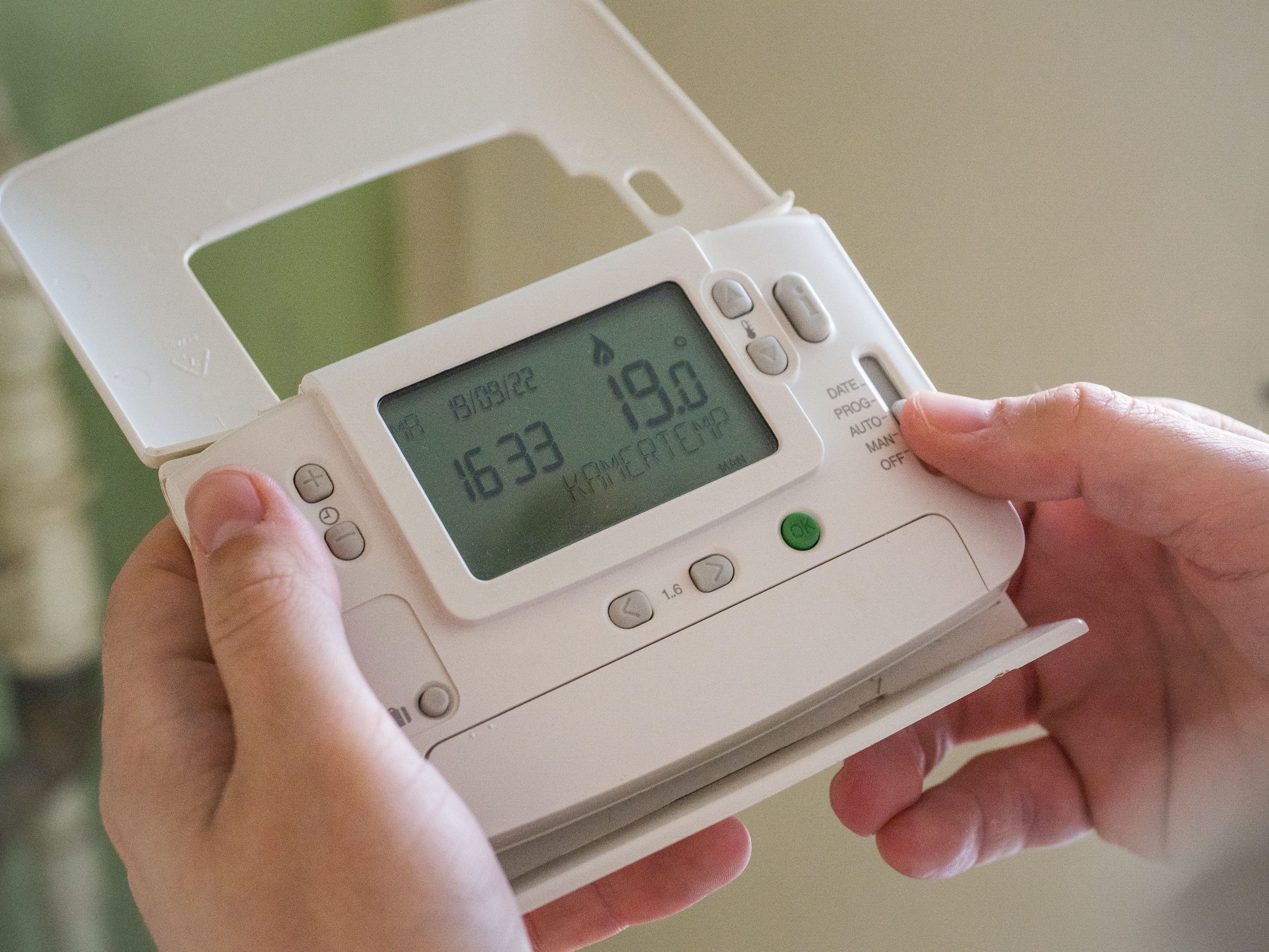 Hands changing a thermostat