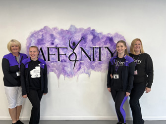 Four women stood in front of a sign affinity