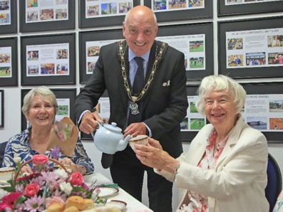 Picture shows Mayor smiling while pouring tea for guests