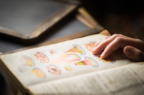 A child's hand looking at one of the historical recipe books in the museum kitchen