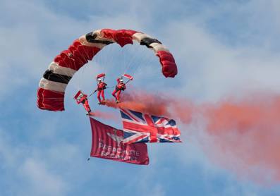 Red Devils mid flight with UK flag and flares